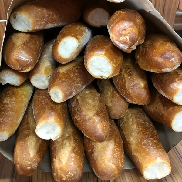 A paper bag filled with many freshly baked, golden-brown bolillo rolls, a Mexican bread.