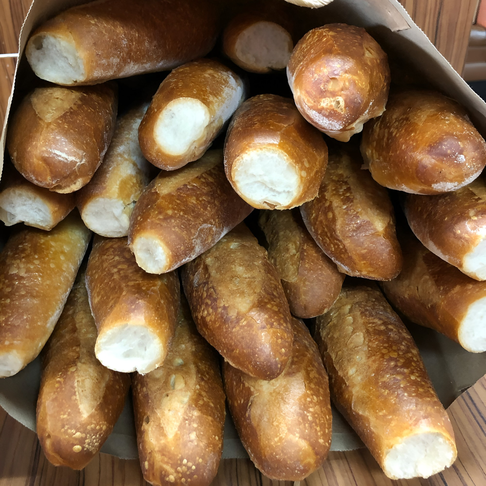 A paper bag filled with many freshly baked, golden-brown bolillo rolls, a Mexican bread.
