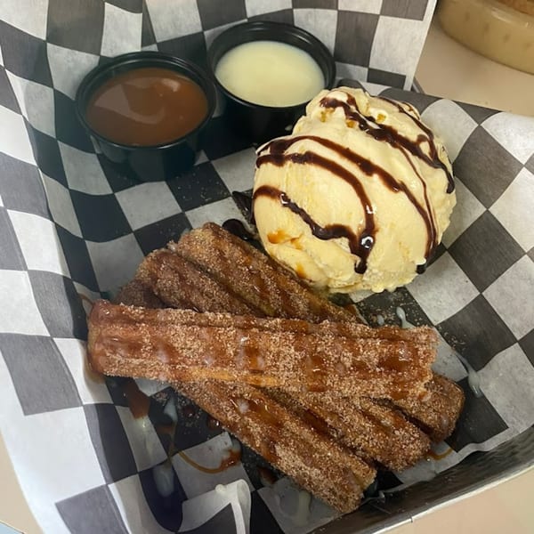 Churros with cinnamon sugar, vanilla ice cream with chocolate drizzle, and two dipping sauces.